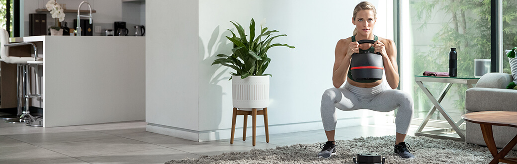 A woman performing a squat with a kettlebell.